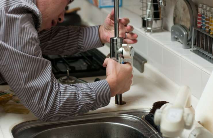 Uomo ripara rubinetto